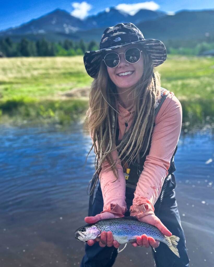 Erica holding a trout as climbing and fly fishing are her favorite activities