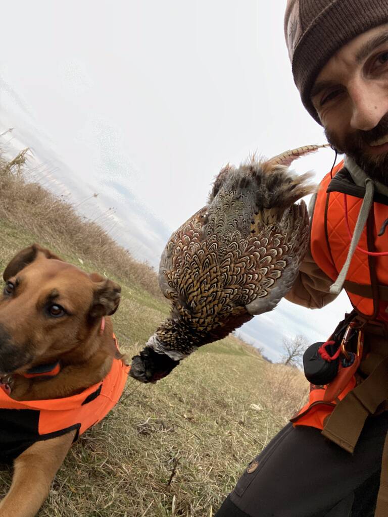 coach kubi and his hunting dog holding a pheasant