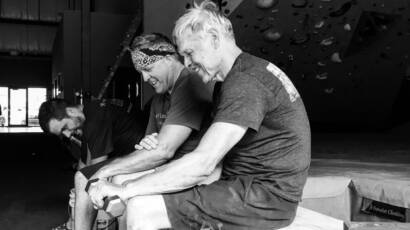 Group of men sitting on a bench in the climbing gym doing wrist curls