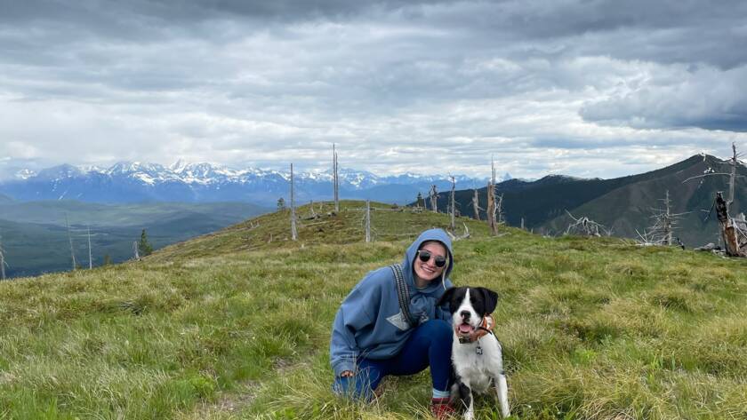 Tess sitting in a field with her dog