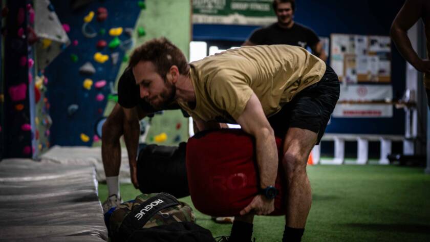 Patrick lifting large sandbag off the ground