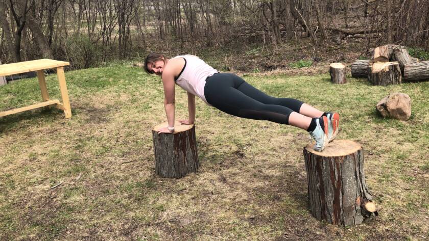 Courtney Weber practicing balance training by planking in the outdoors.