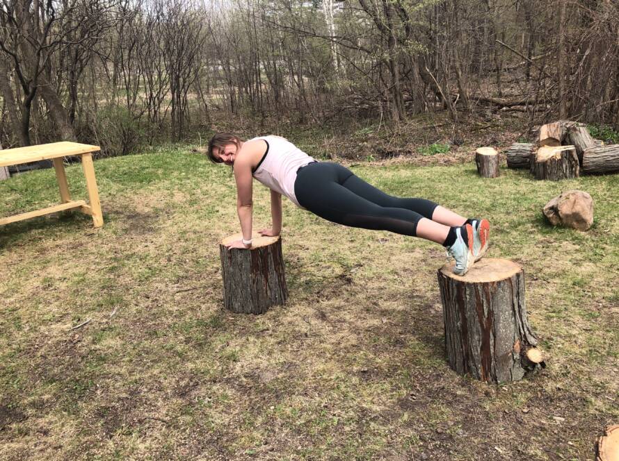 Courtney Weber practicing balance training by planking in the outdoors.