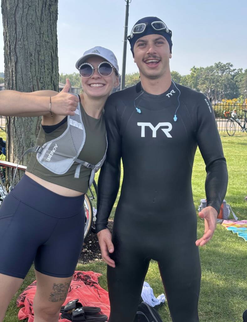Photo of Megan in her running gear before the triathlon relay, posing with Coach Adam, ready to take on the full triathlon, himself. Both of them chased new goals for this day.